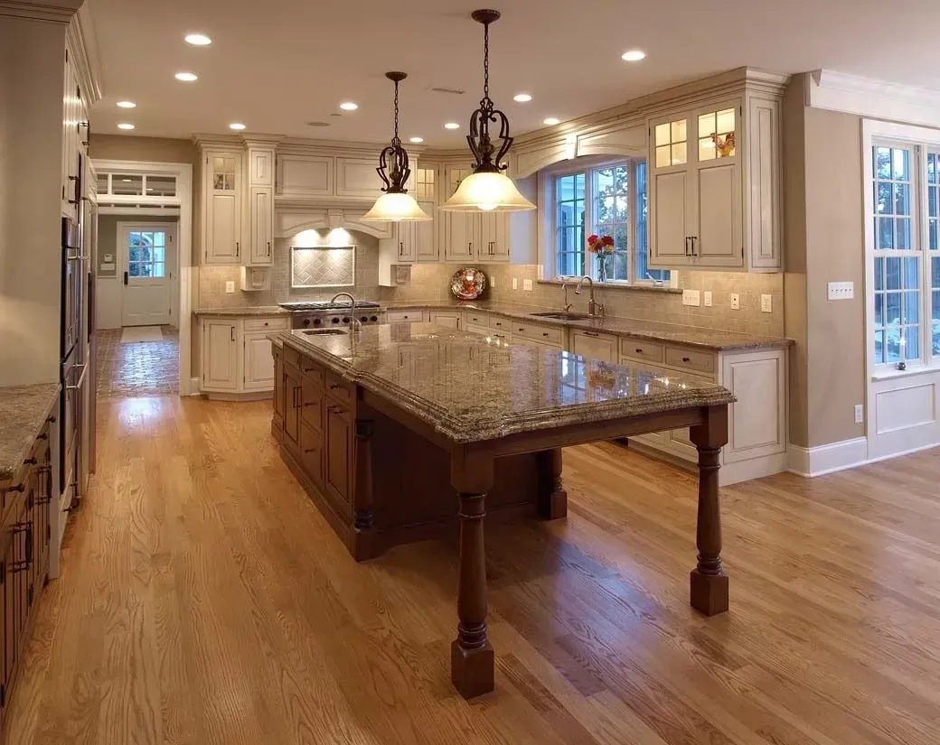 Spacious kitchen with wood floors, island, granite countertops, cream cabinets, and pendant lights.