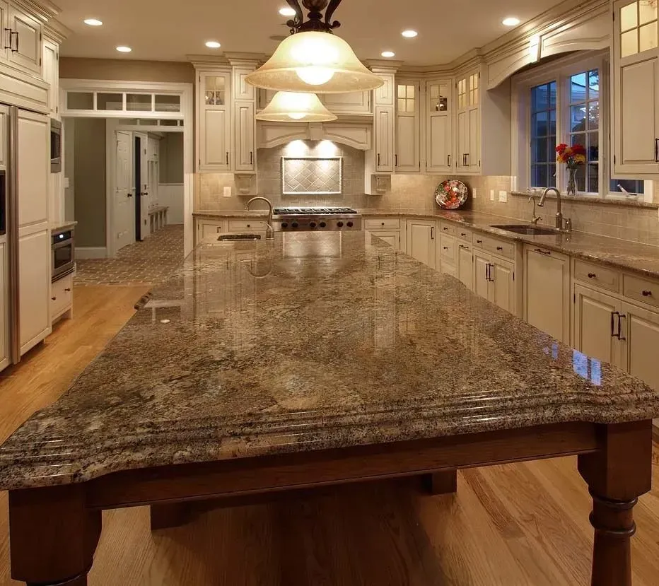 Spacious kitchen with a large granite island and cream-colored cabinets; wooden floor.