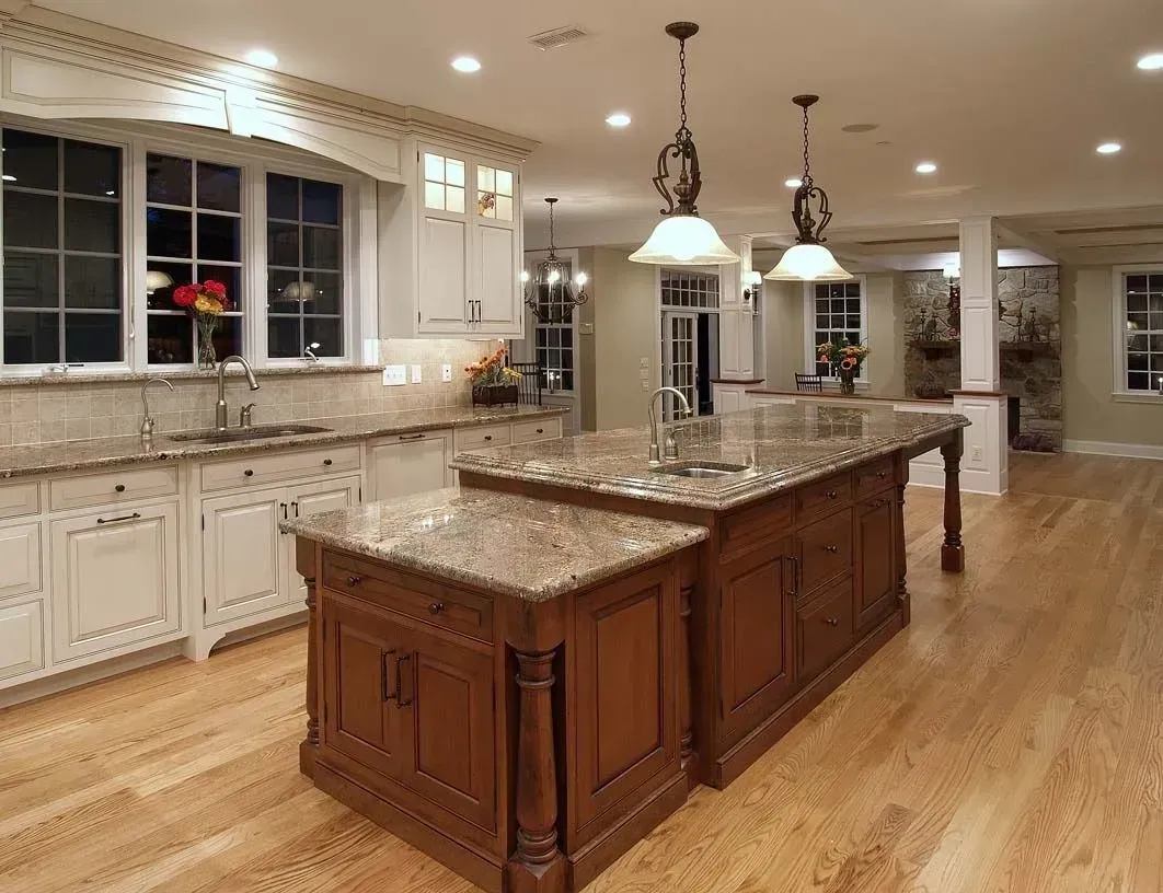 Spacious kitchen with wood cabinets, granite countertops, and two islands; bright lighting.