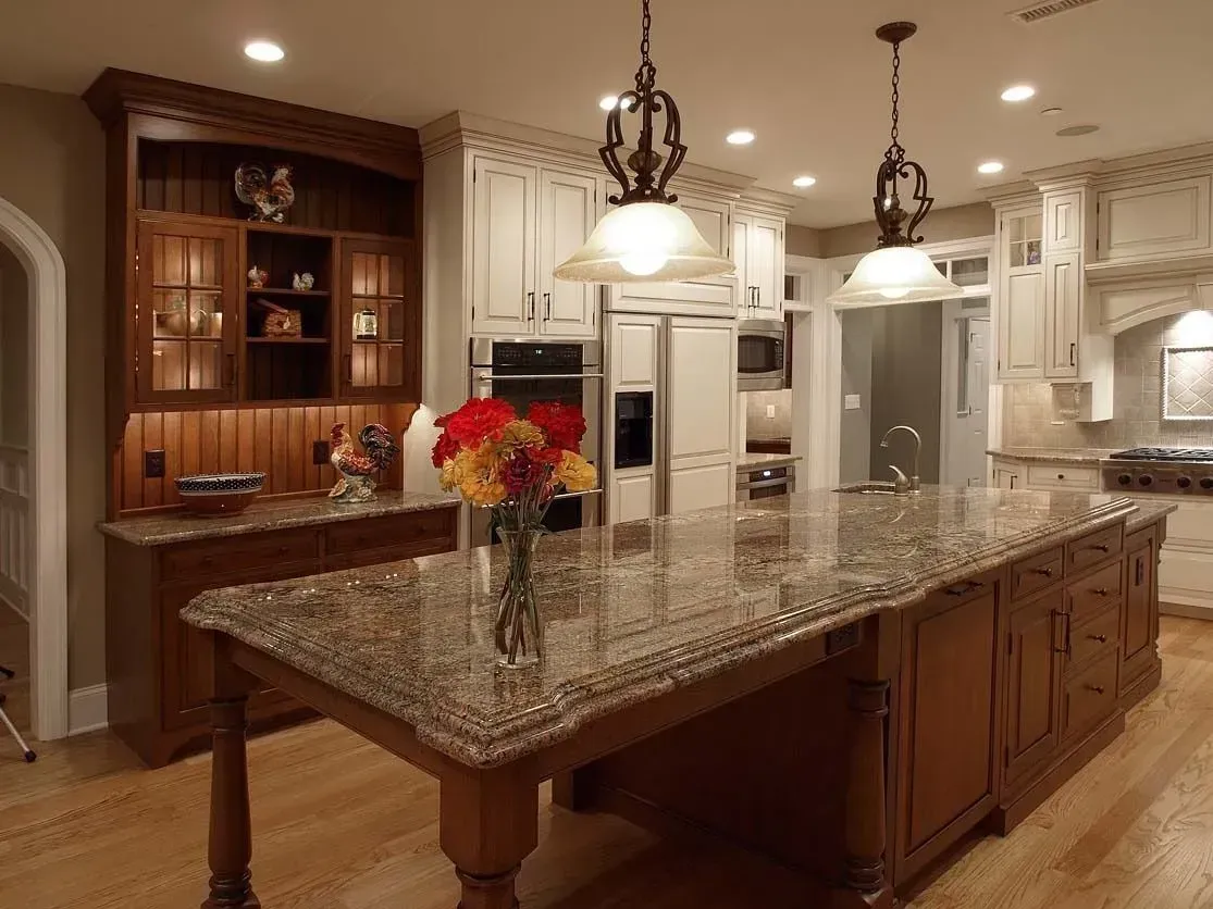 Spacious kitchen with a granite island, wooden cabinets, and two pendant lights.
