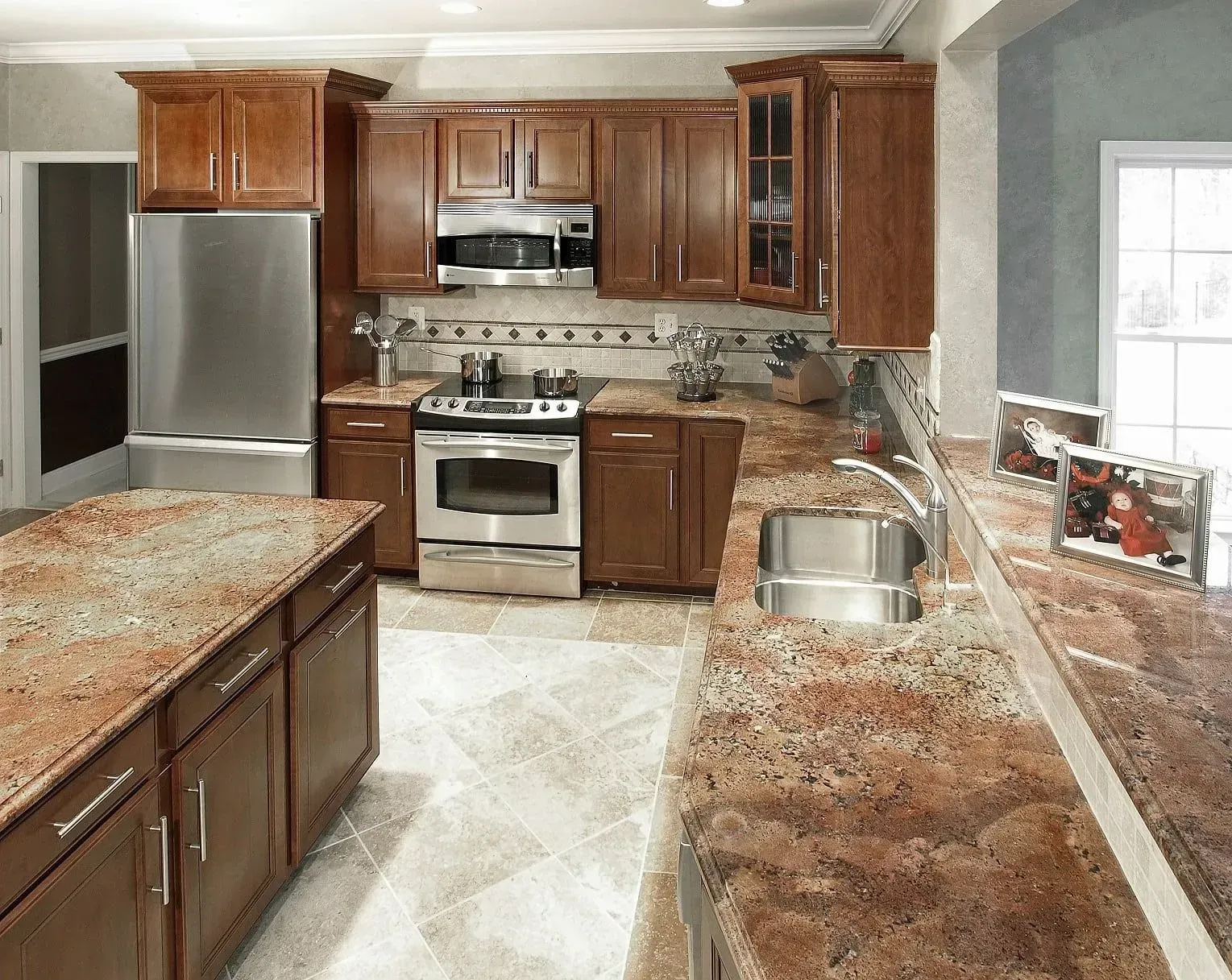 A kitchen with brown cabinets, stainless steel appliances, granite countertops, and tiled floor.
