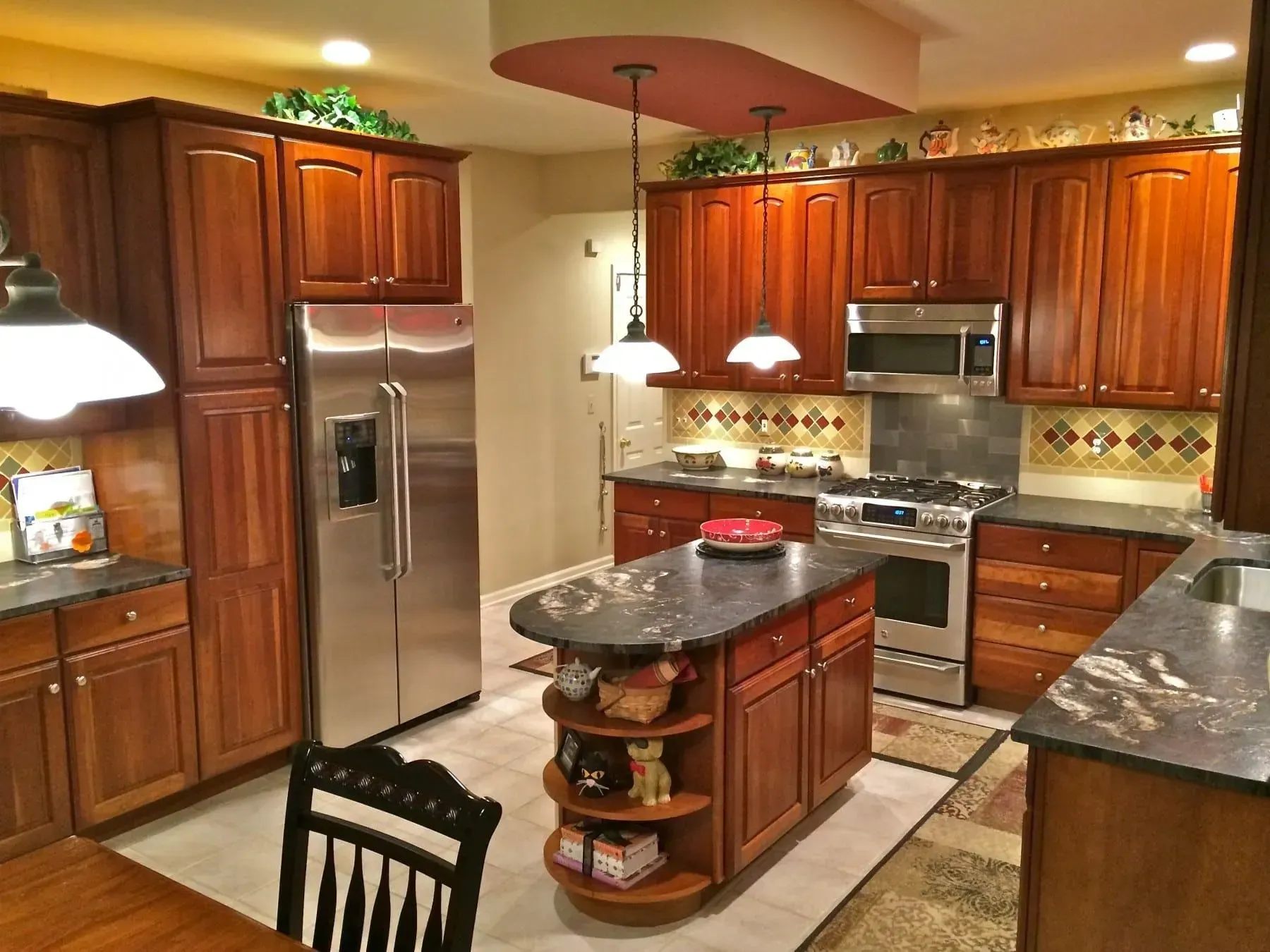Kitchen with cherry cabinets, stainless steel appliances, dark countertops, and an island.
