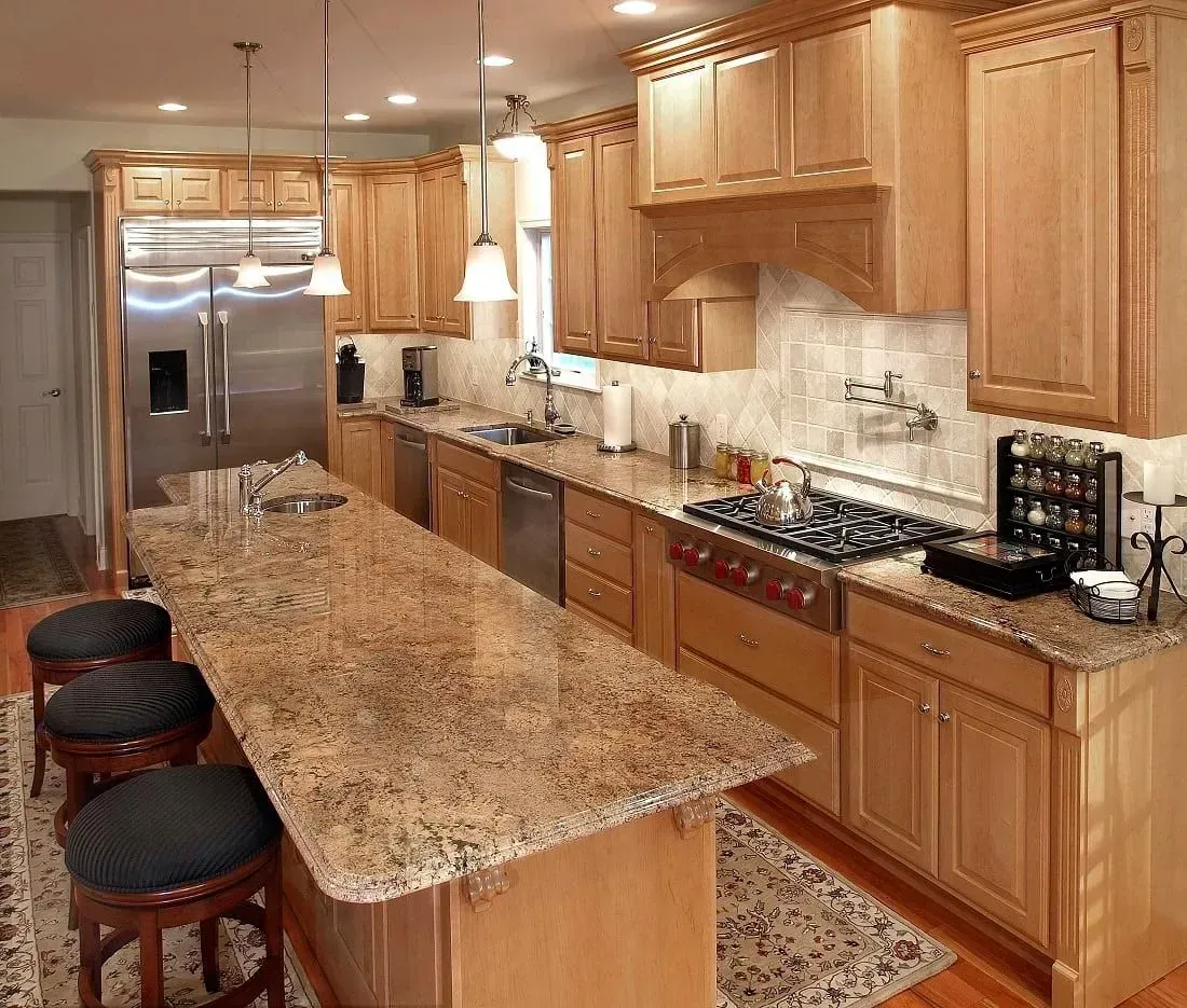 Spacious kitchen with light wood cabinets, granite countertops, and a stainless steel refrigerator.