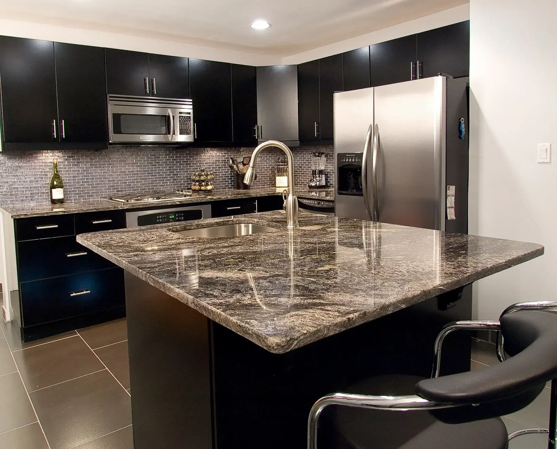 Modern kitchen with black cabinets, granite countertops, and stainless steel appliances.