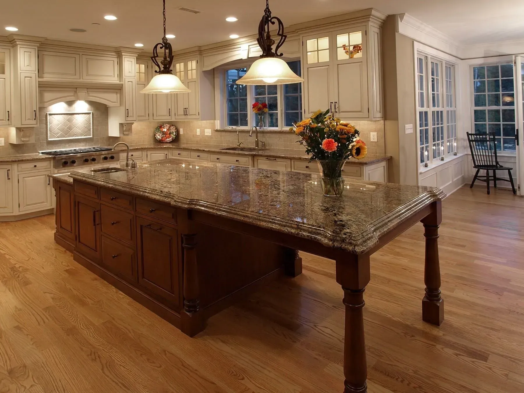 Elegant kitchen with a large island, granite countertops, and light wood flooring.