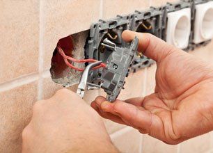 Electrician hands repairing wires of a wall fixture using pliers