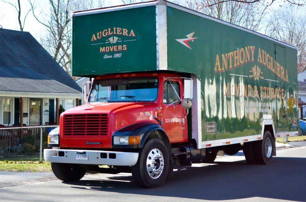 A red and green moving truck is parked on the side of the road
