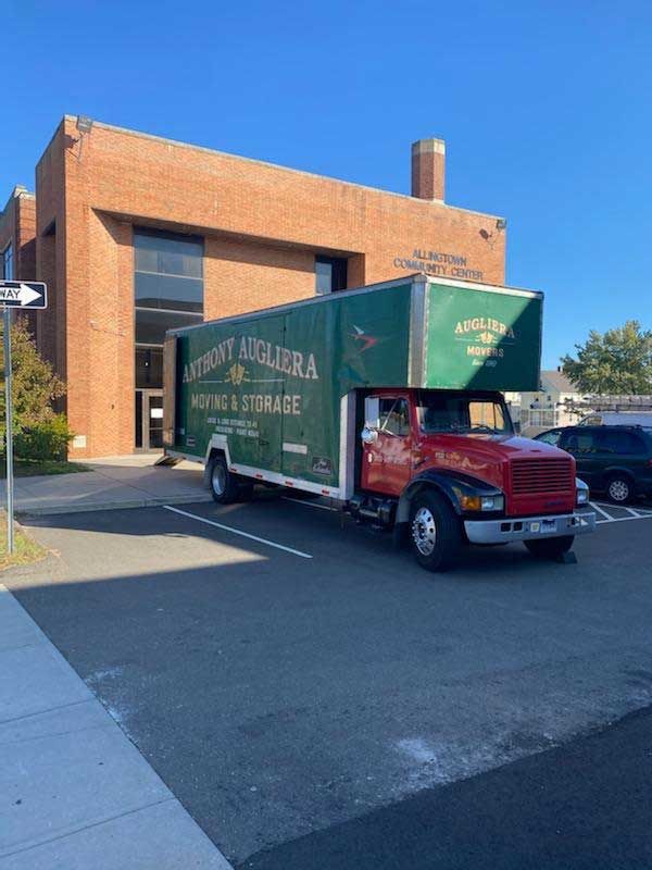 A moving truck is parked in front of a brick building