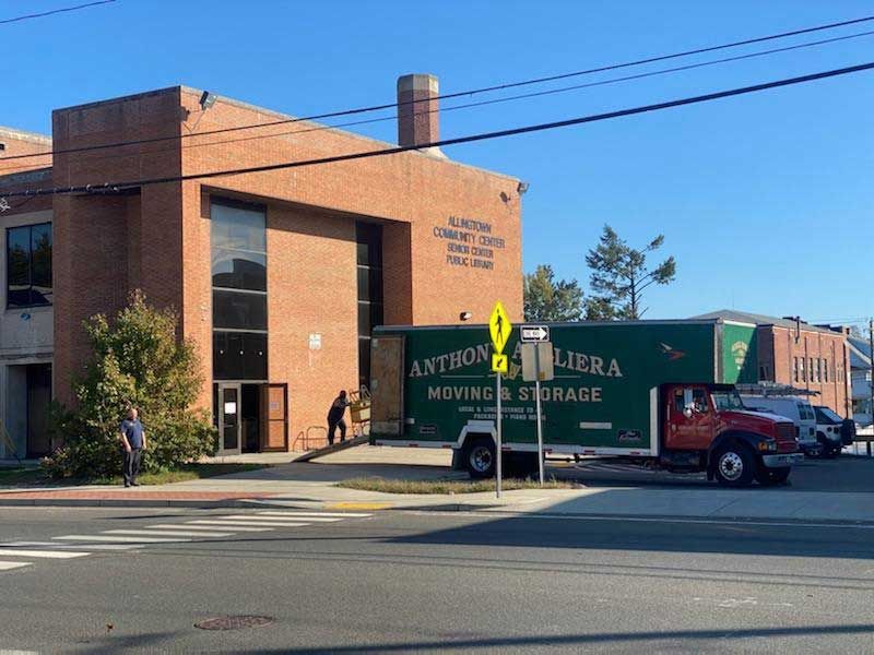 A green anthony liera moving truck is parked in front of a brick building