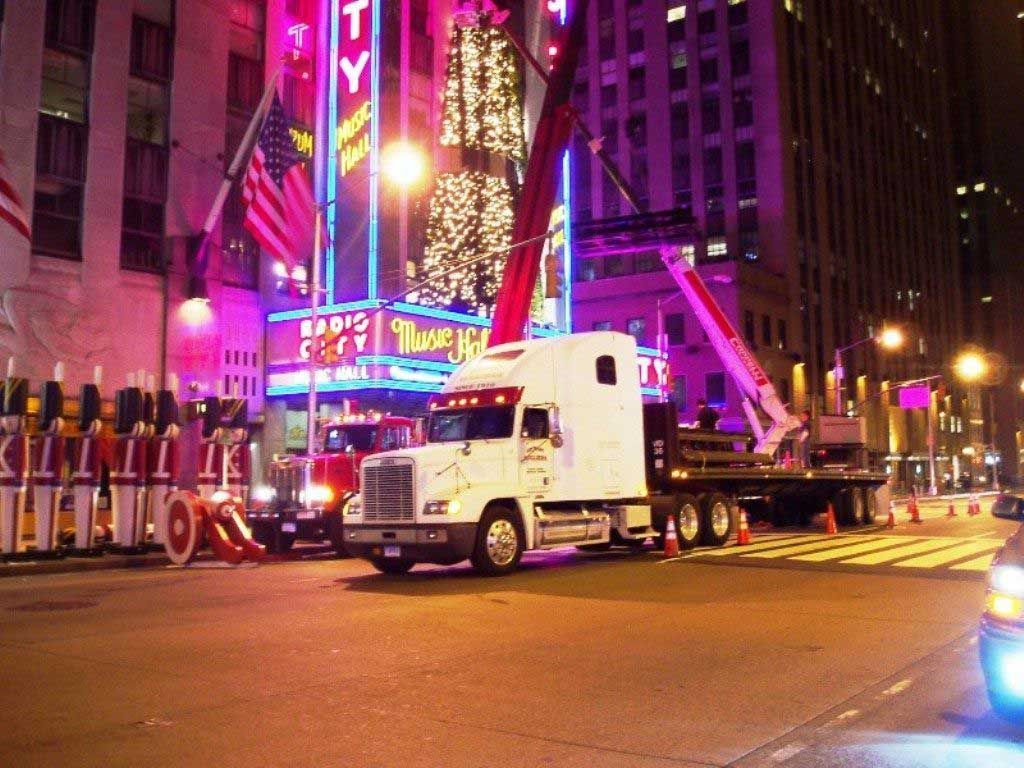 A white semi truck is driving down a city street at night