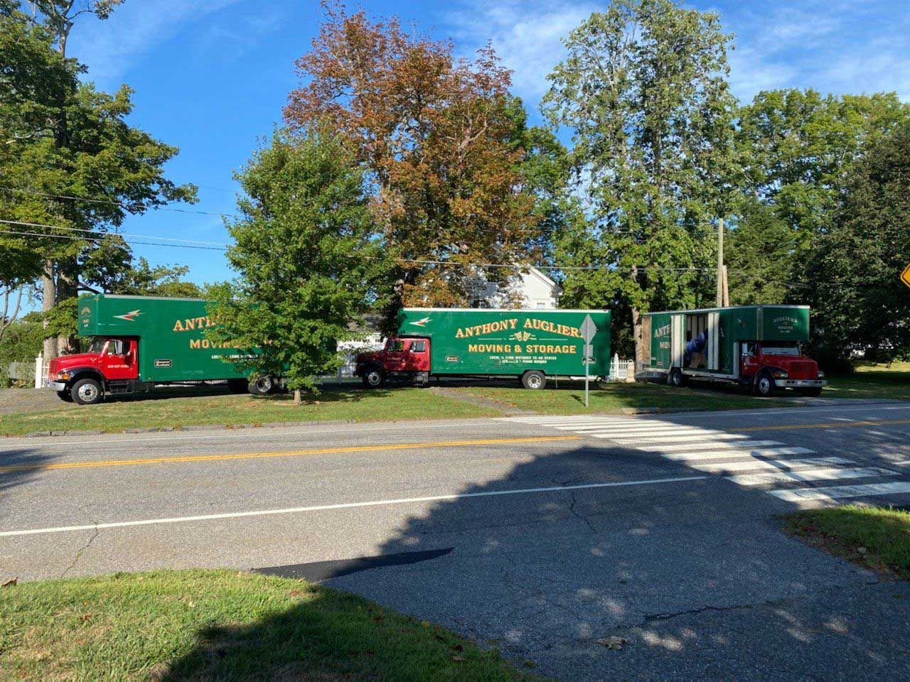 Two moving trucks are parked on the side of the road