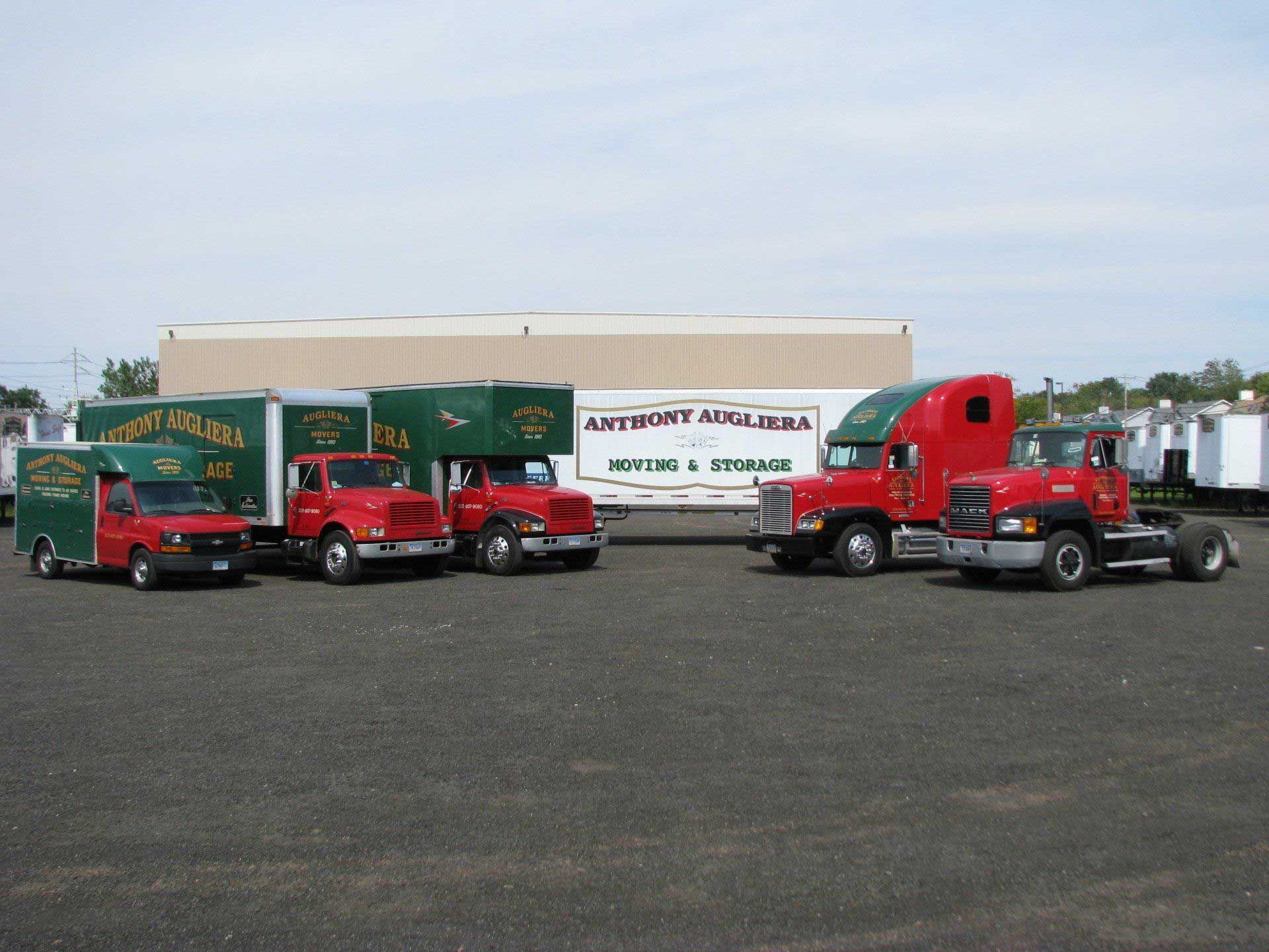 A row of moving trucks are parked in a parking lot