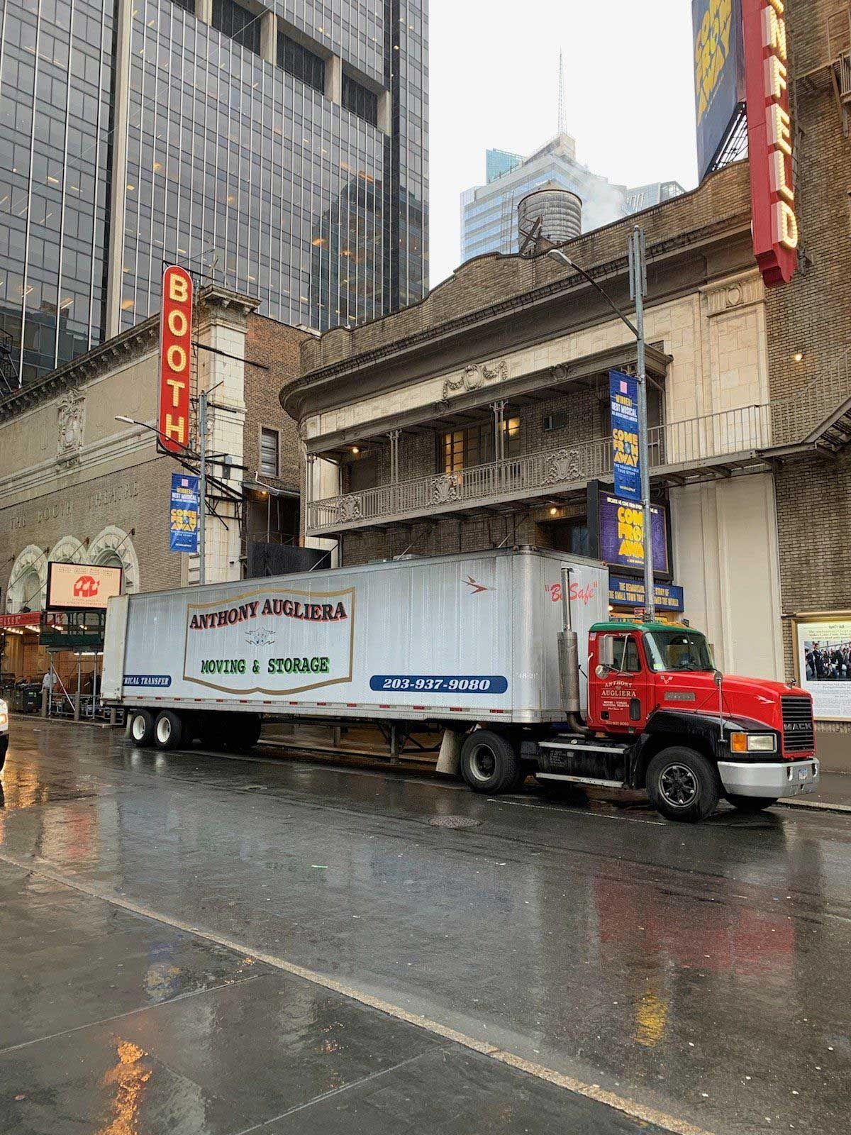 A red and white truck is parked in front of a building.