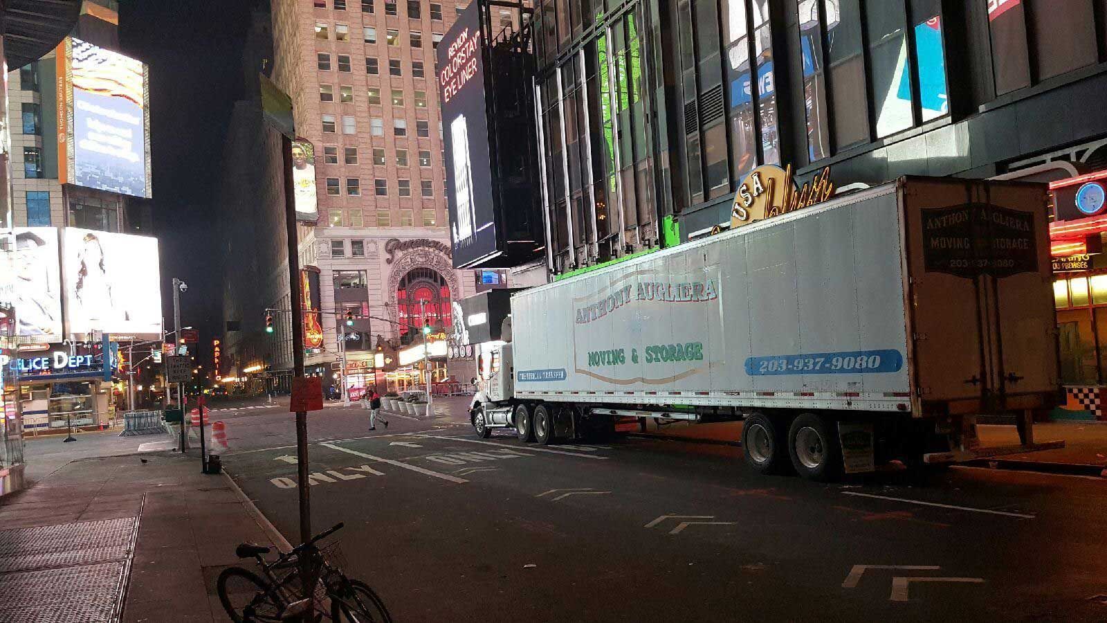 A large white truck is driving down a city street at night.