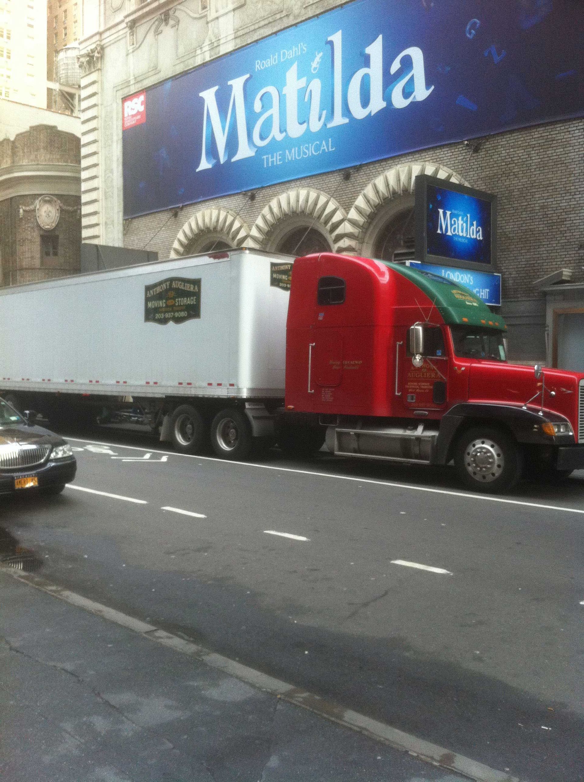 A red semi truck is parked in front of a building that says matilda