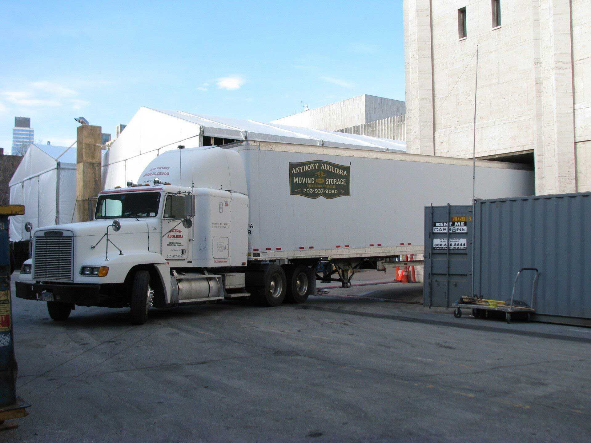 A white semi truck is parked in front of a building