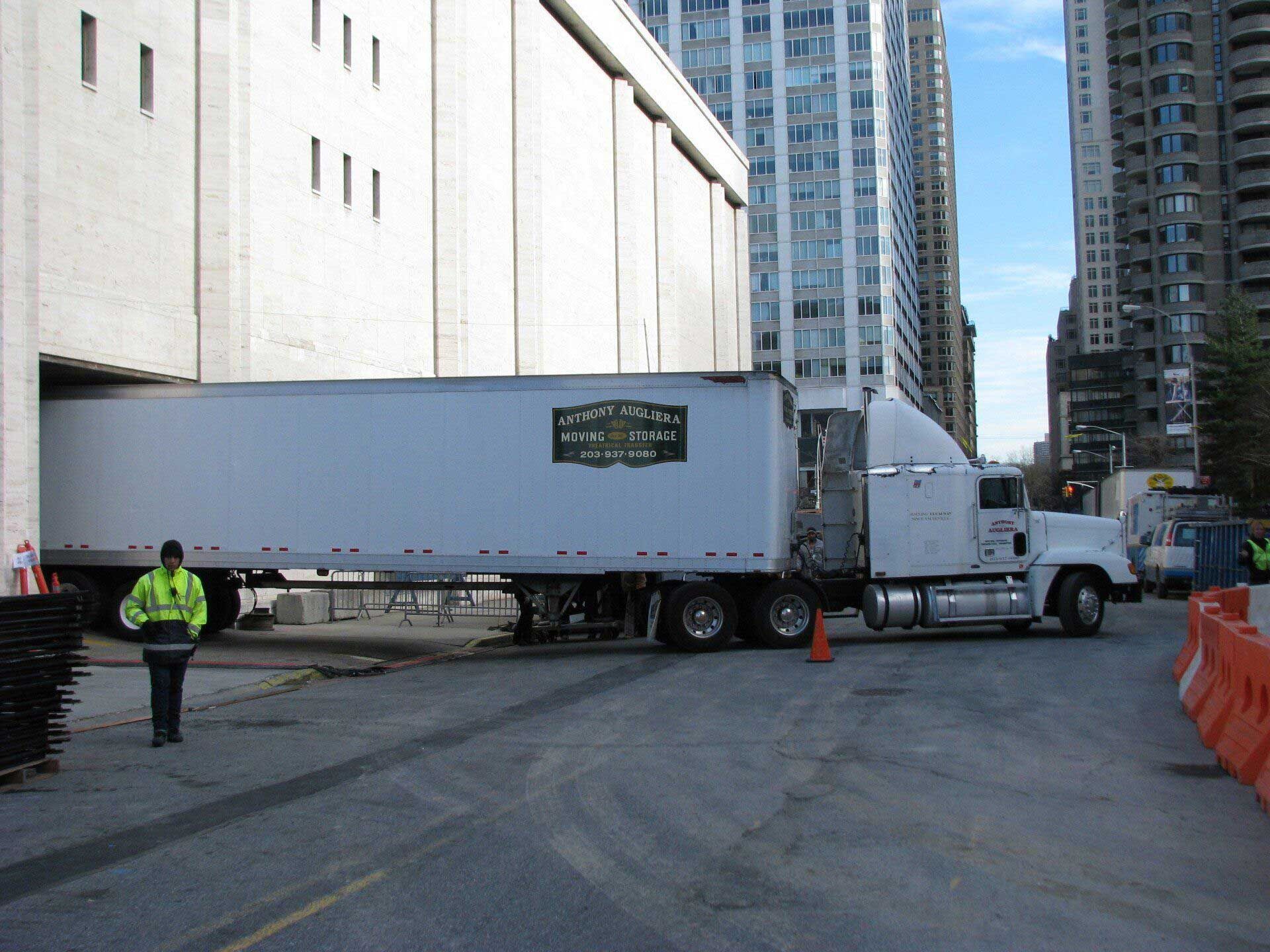 A white semi truck is parked in front of a building
