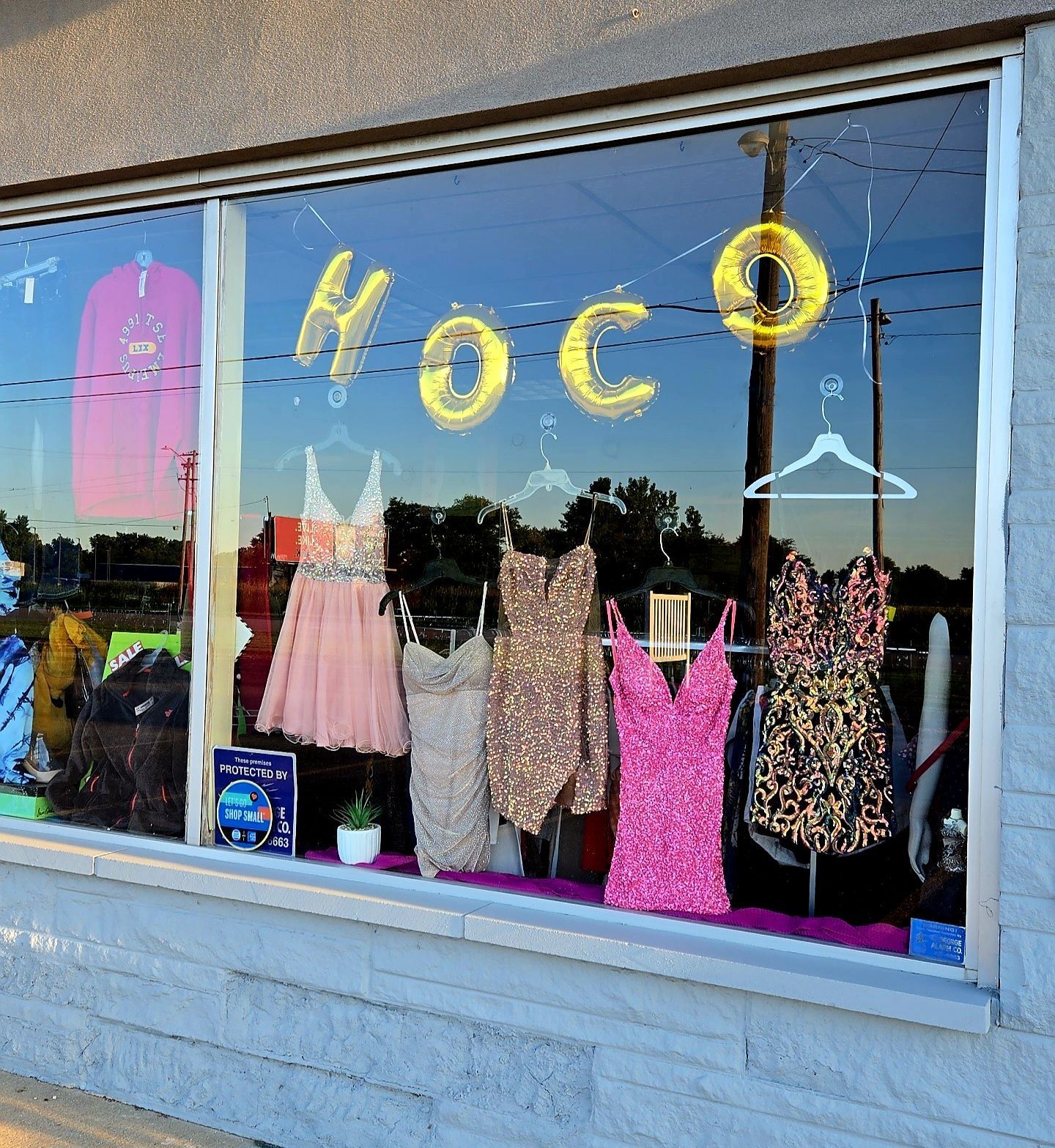 Window display advertising for Homecoming with dresses in various colors. HOCO balloons are displayed.