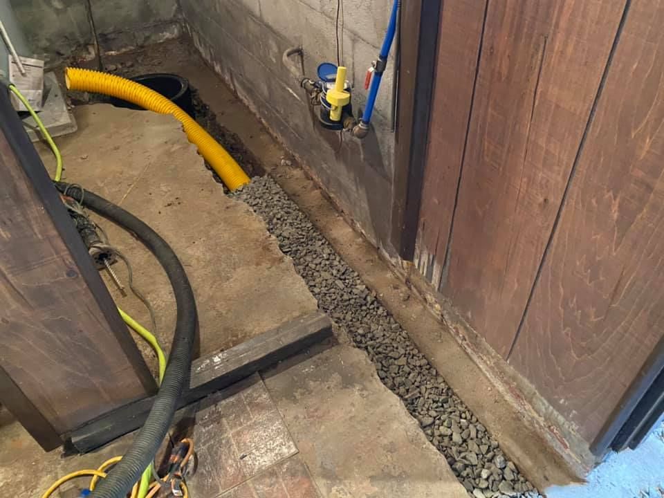 A yellow hose is sitting on the floor next to a wooden wall.
