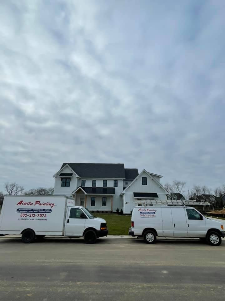 two white vans are parked in front of a house .