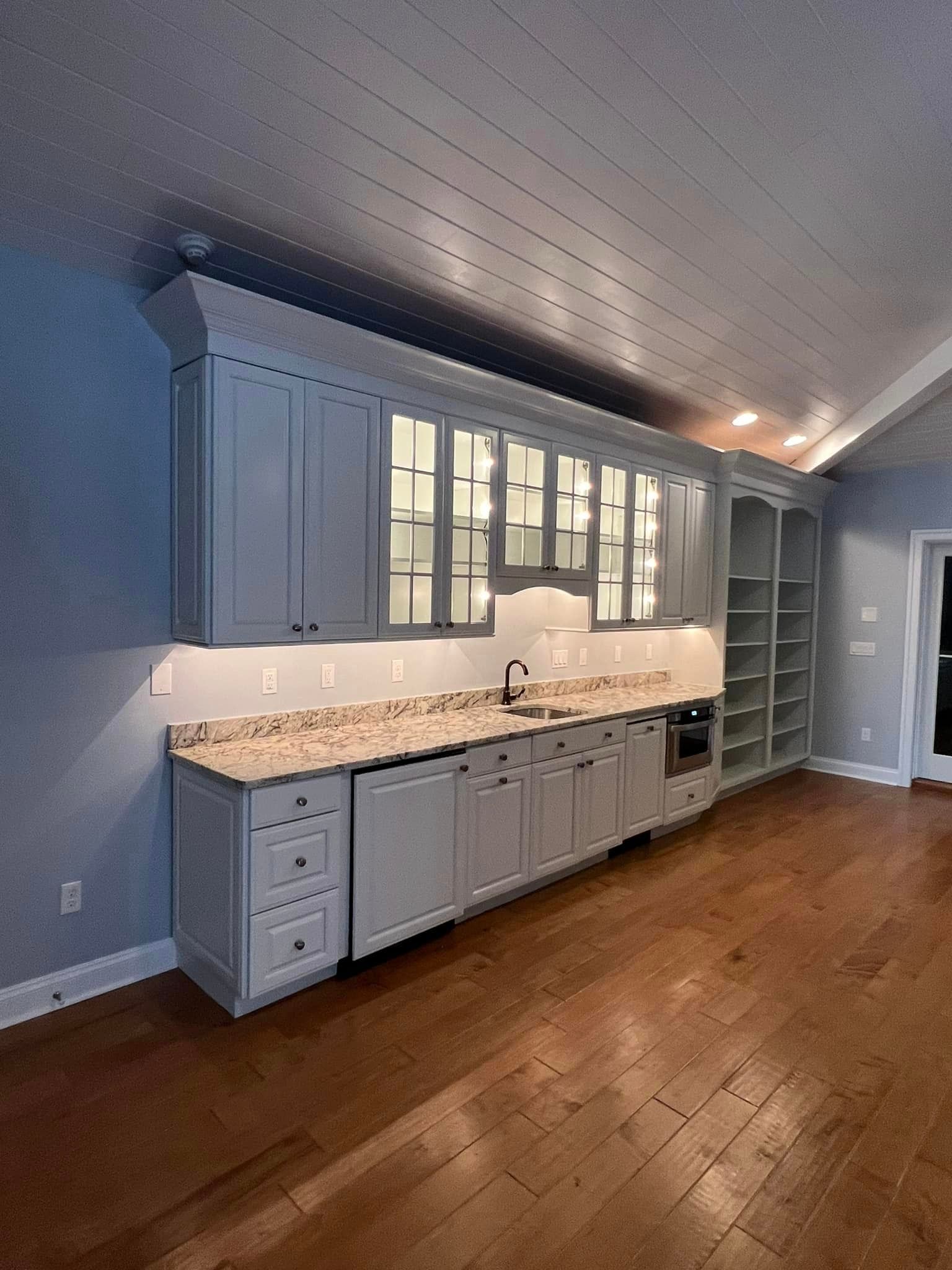 a kitchen with white cabinets , granite counter tops , and hardwood floors .