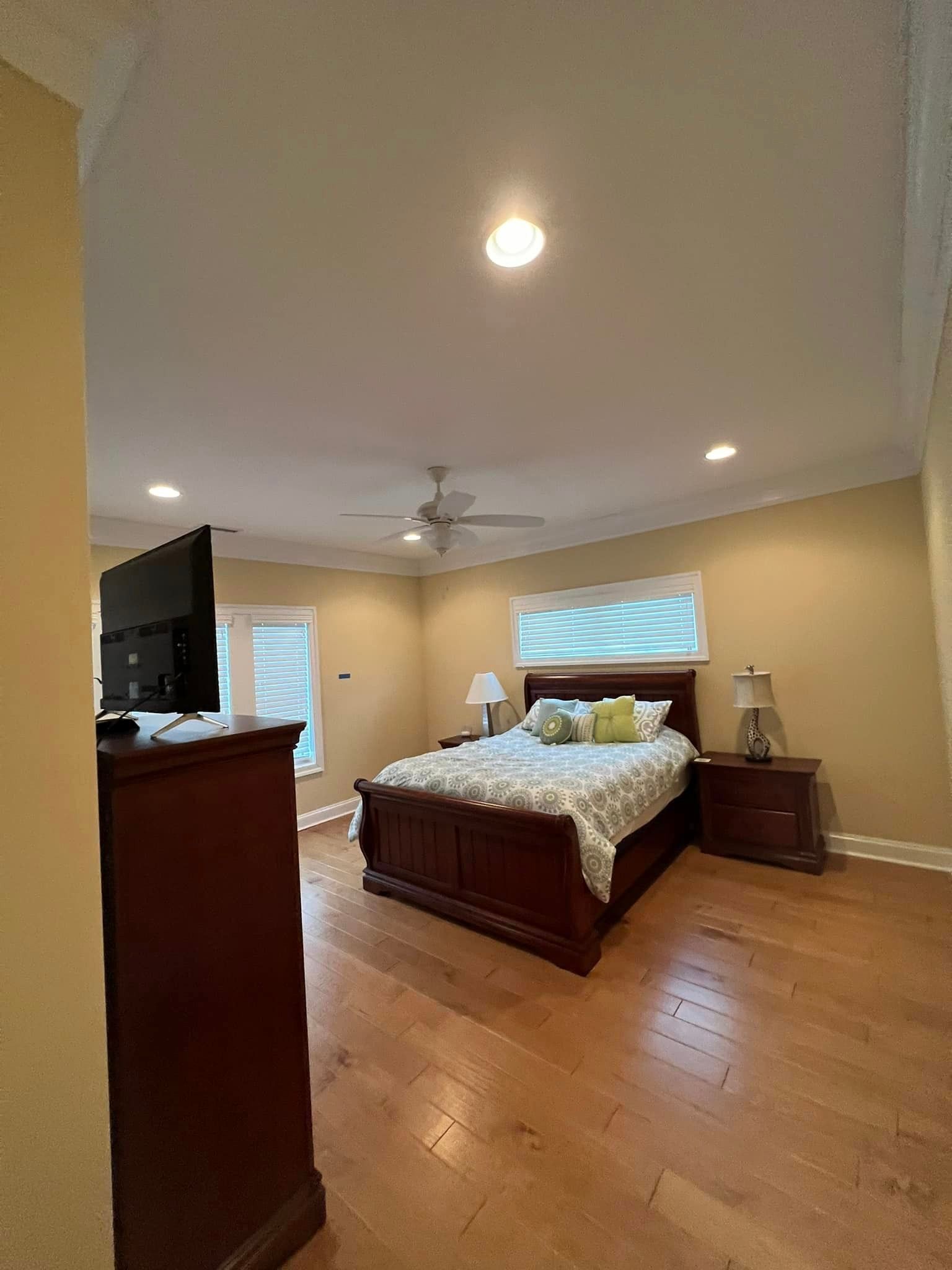 a bedroom with a bed , dresser , nightstand , television and ceiling fan .
