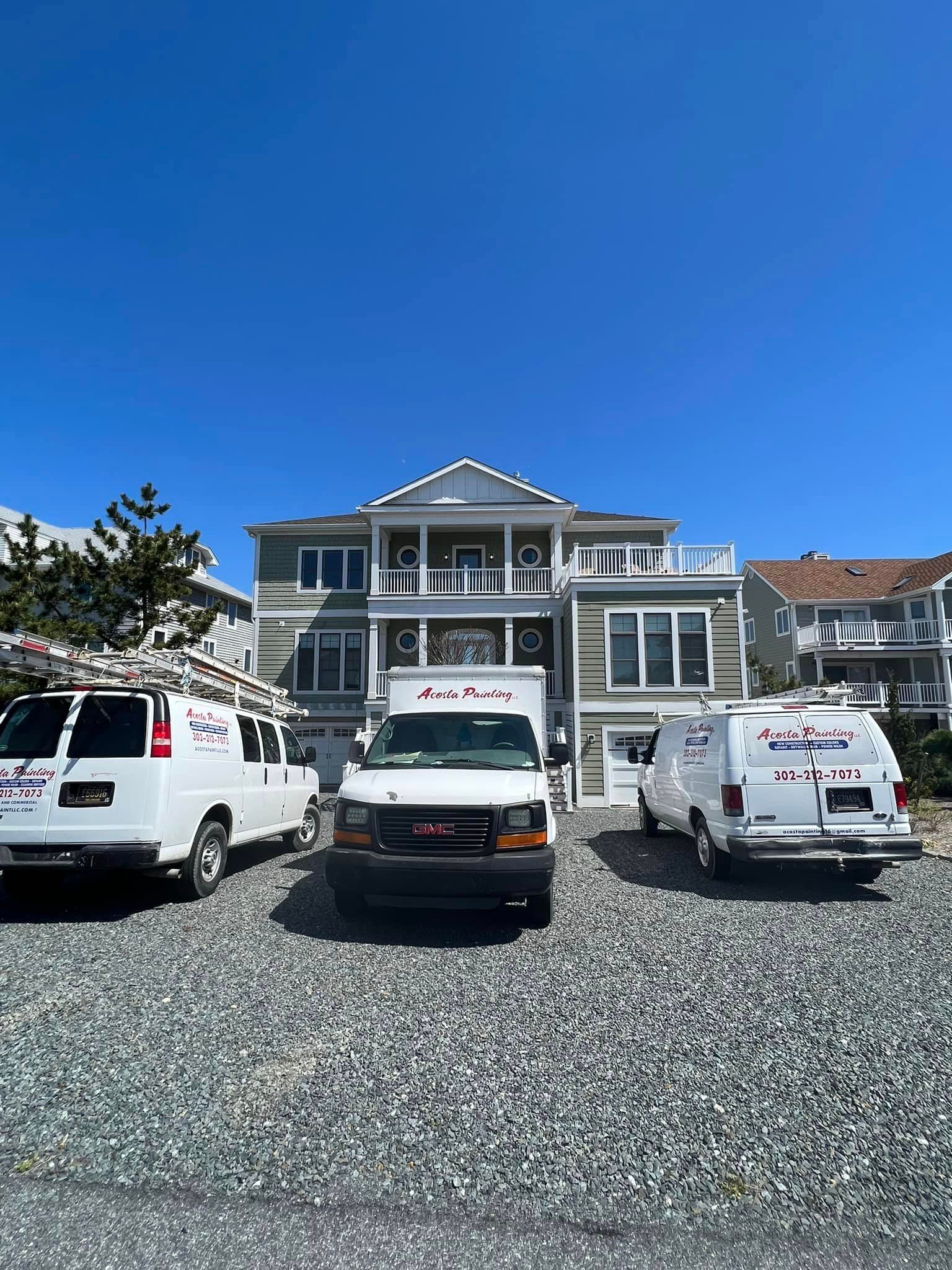 three white vans are parked in front of a large house .