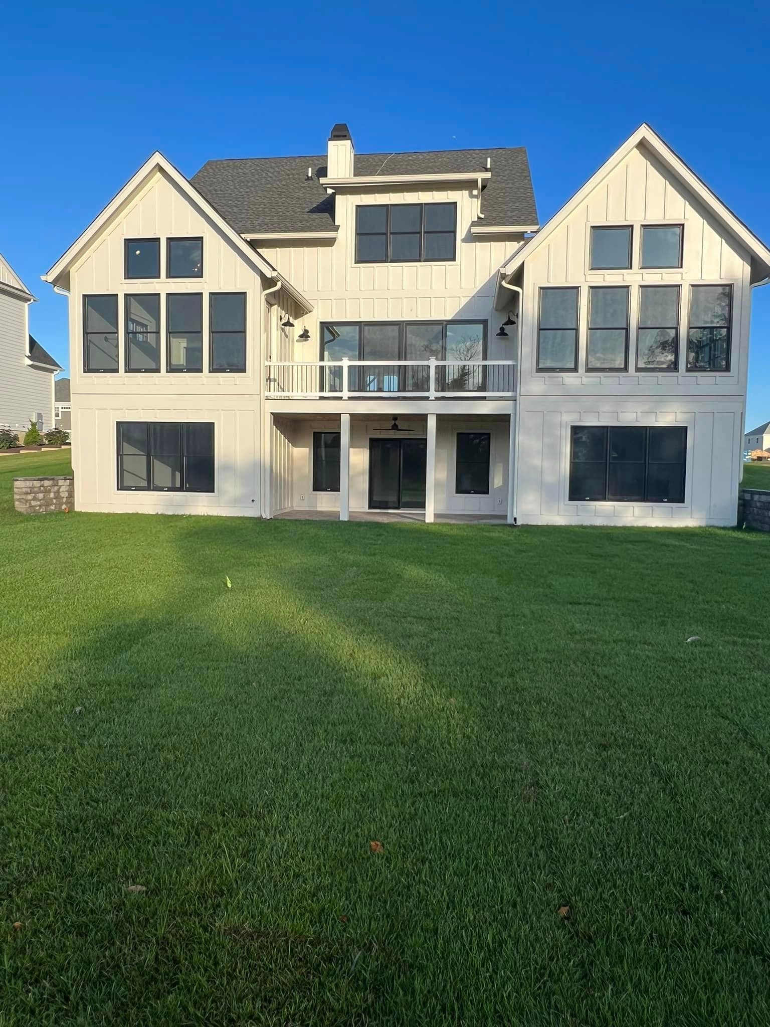 a large white house with a lot of windows is sitting on top of a lush green hill .