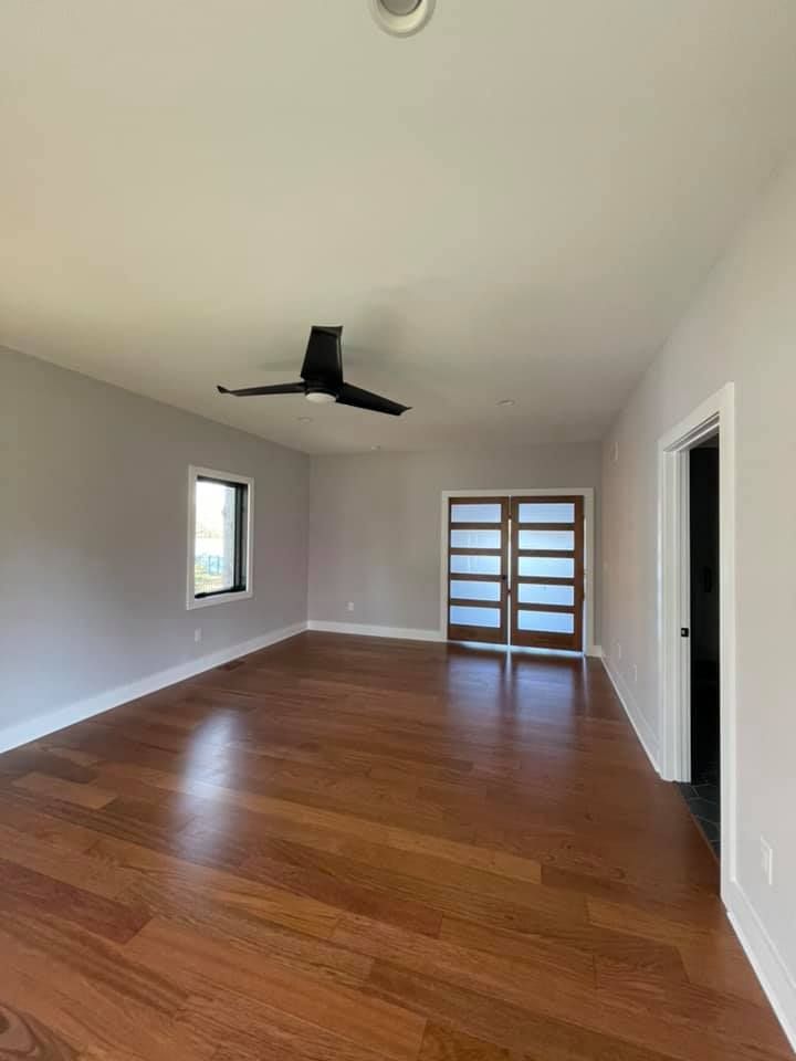 an empty living room with hardwood floors and a ceiling fan .