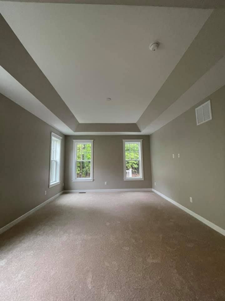 a large empty room with a vaulted ceiling and two windows .
