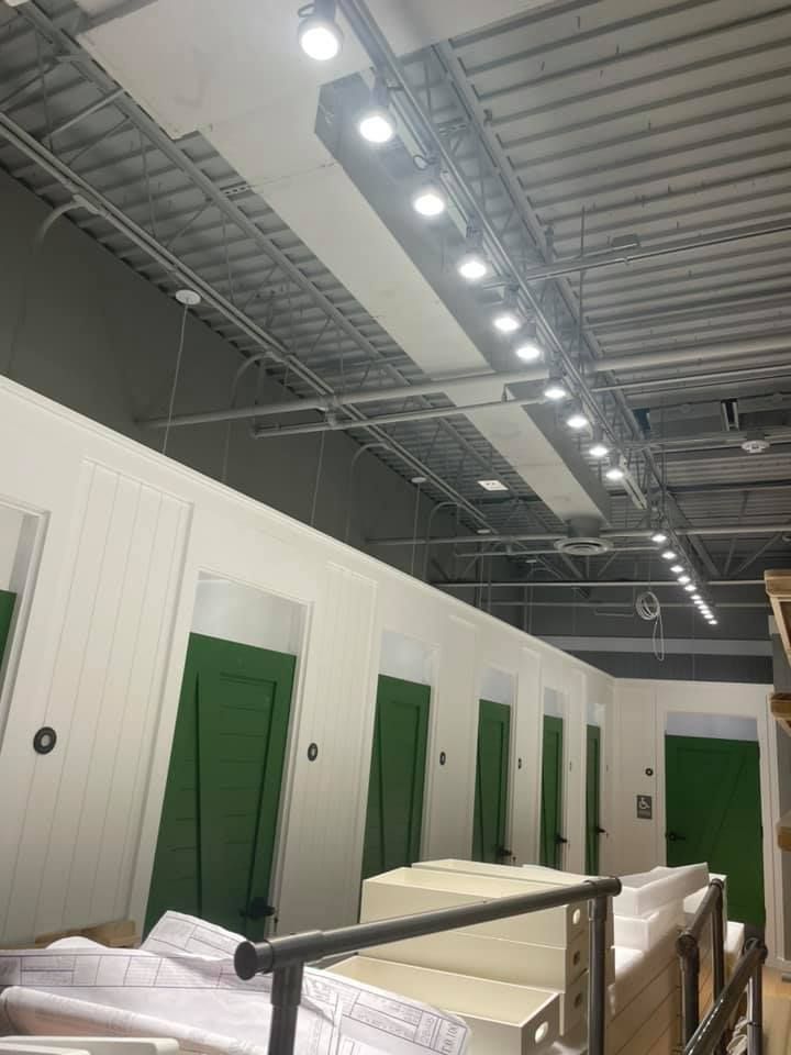 a warehouse with green doors and white walls has a lot of lights on the ceiling .