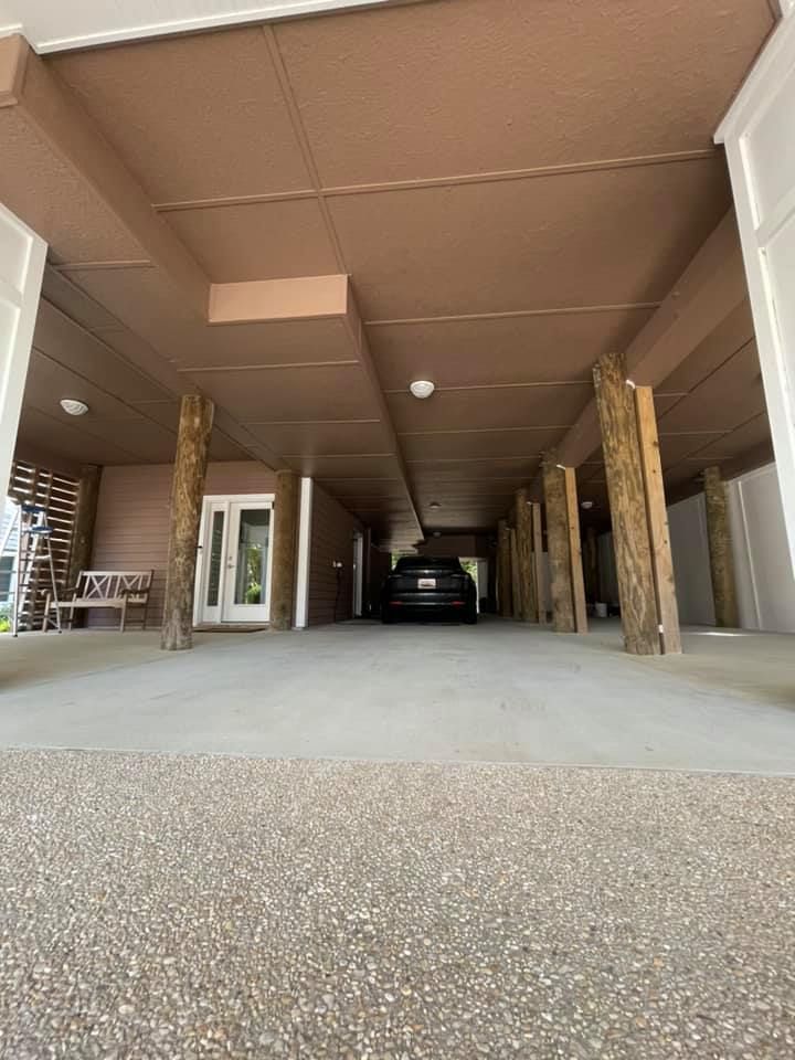 a car is parked in a garage under a porch .