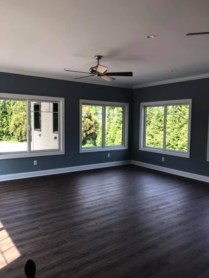 an empty living room with a ceiling fan and lots of windows .