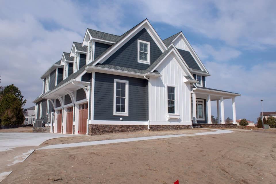 a large blue and white house is sitting on top of a dirt field .