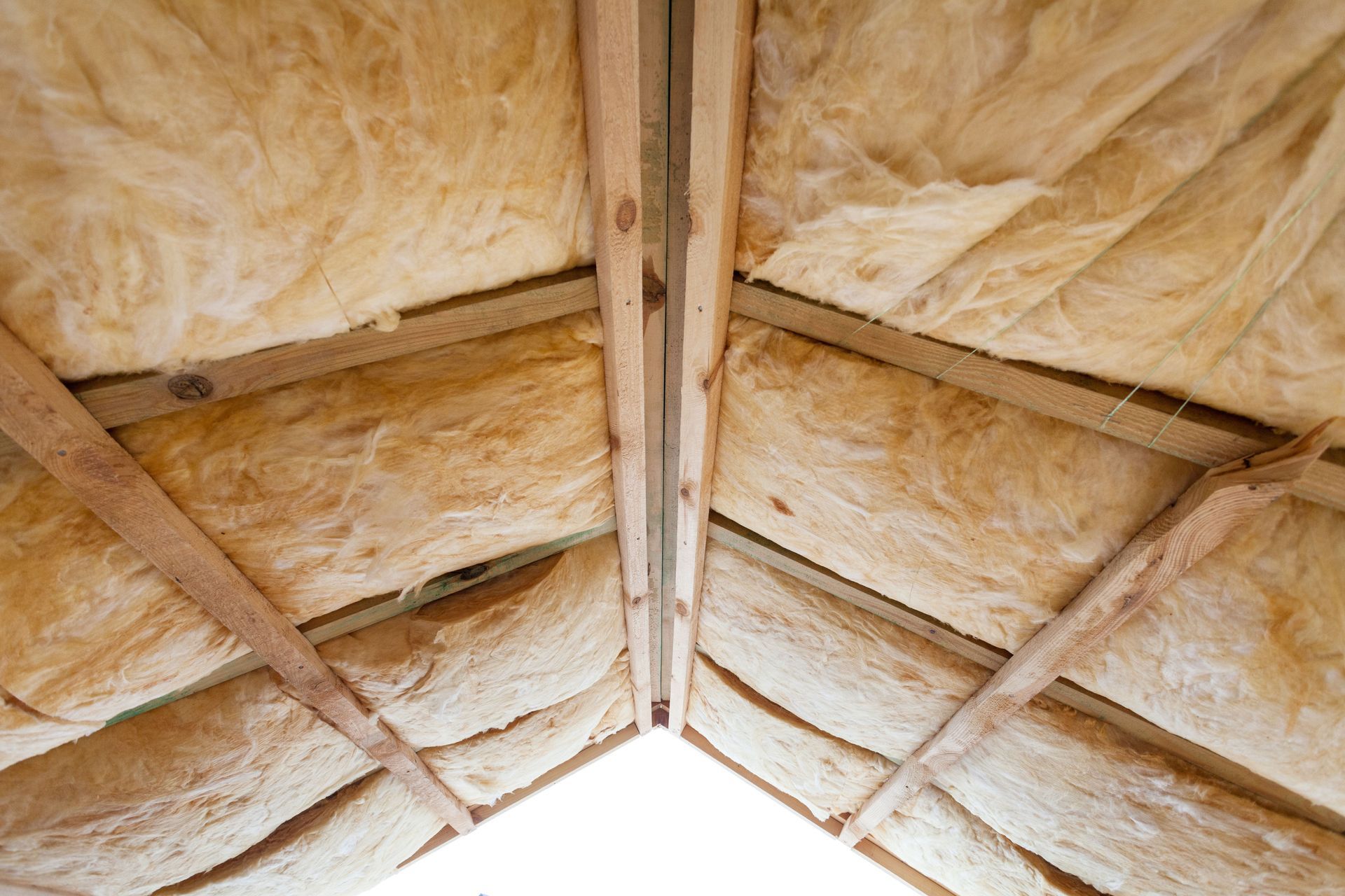 Insulated attic roof with exposed wooden rafters and beige insulation panels