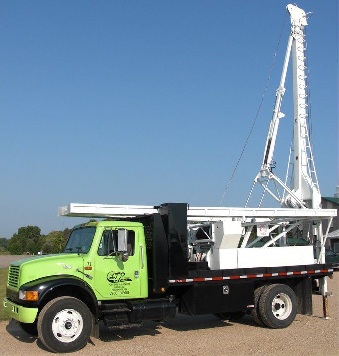 A green truck is parked next to a white crane