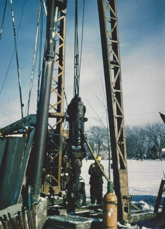 A man in a yellow hard hat stands in front of a large machine