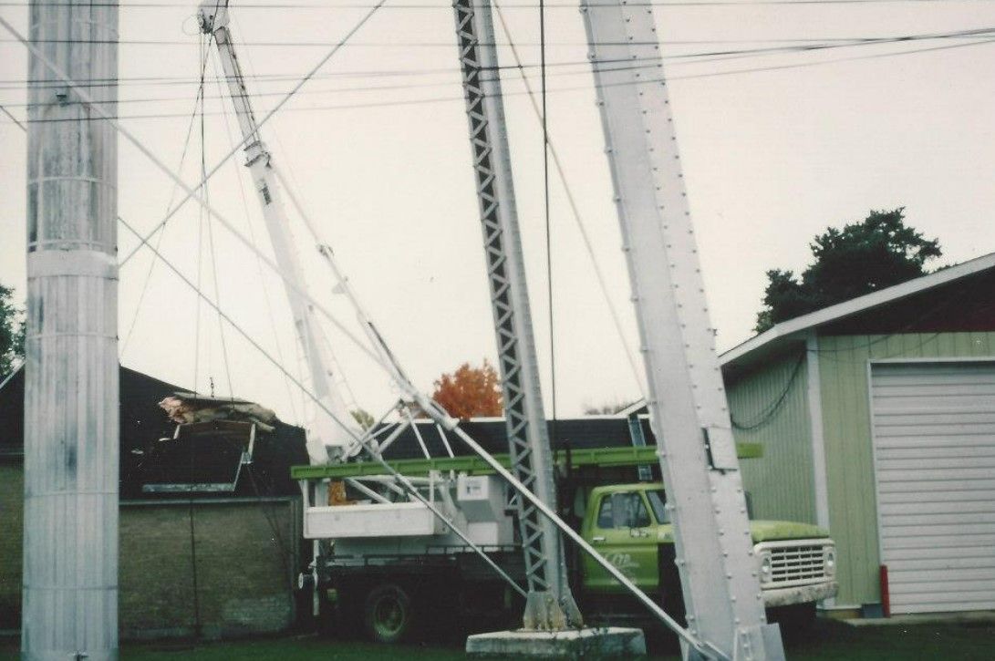 A green truck is parked next to a white pole