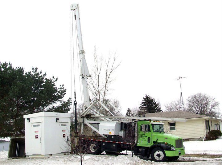 A green truck is parked in front of a house