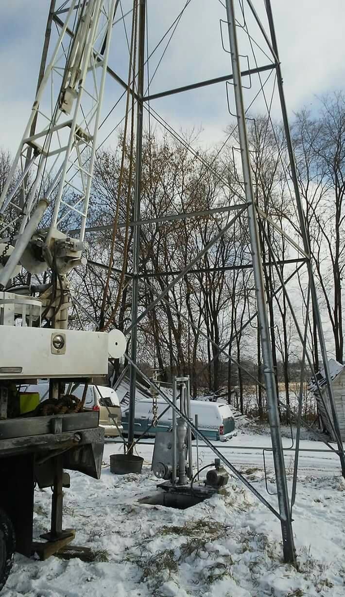 A crane is sitting in the snow next to a tower.
