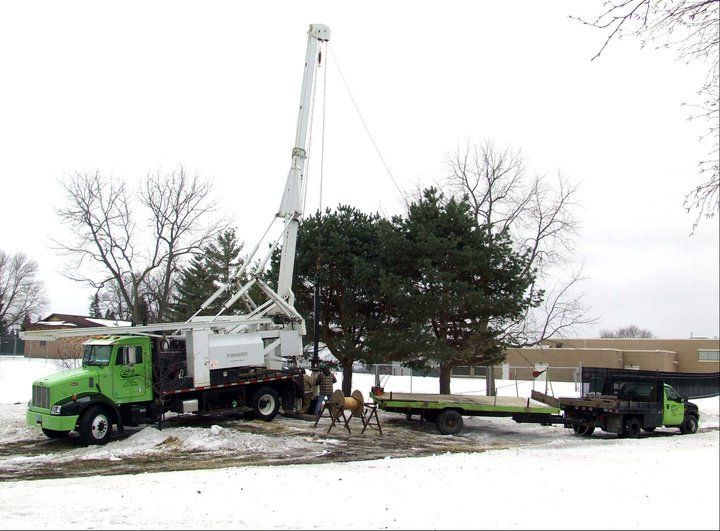 A green truck with a crane attached to it