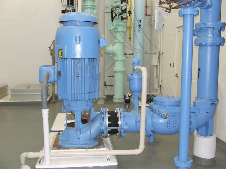 A blue pump is sitting in a room with pipes