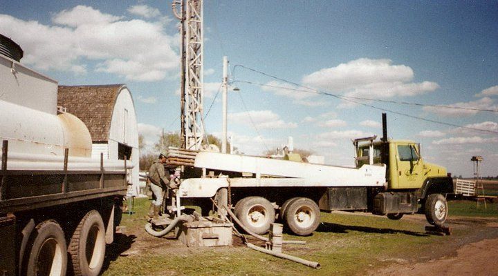 A yellow truck is parked next to a water tank.