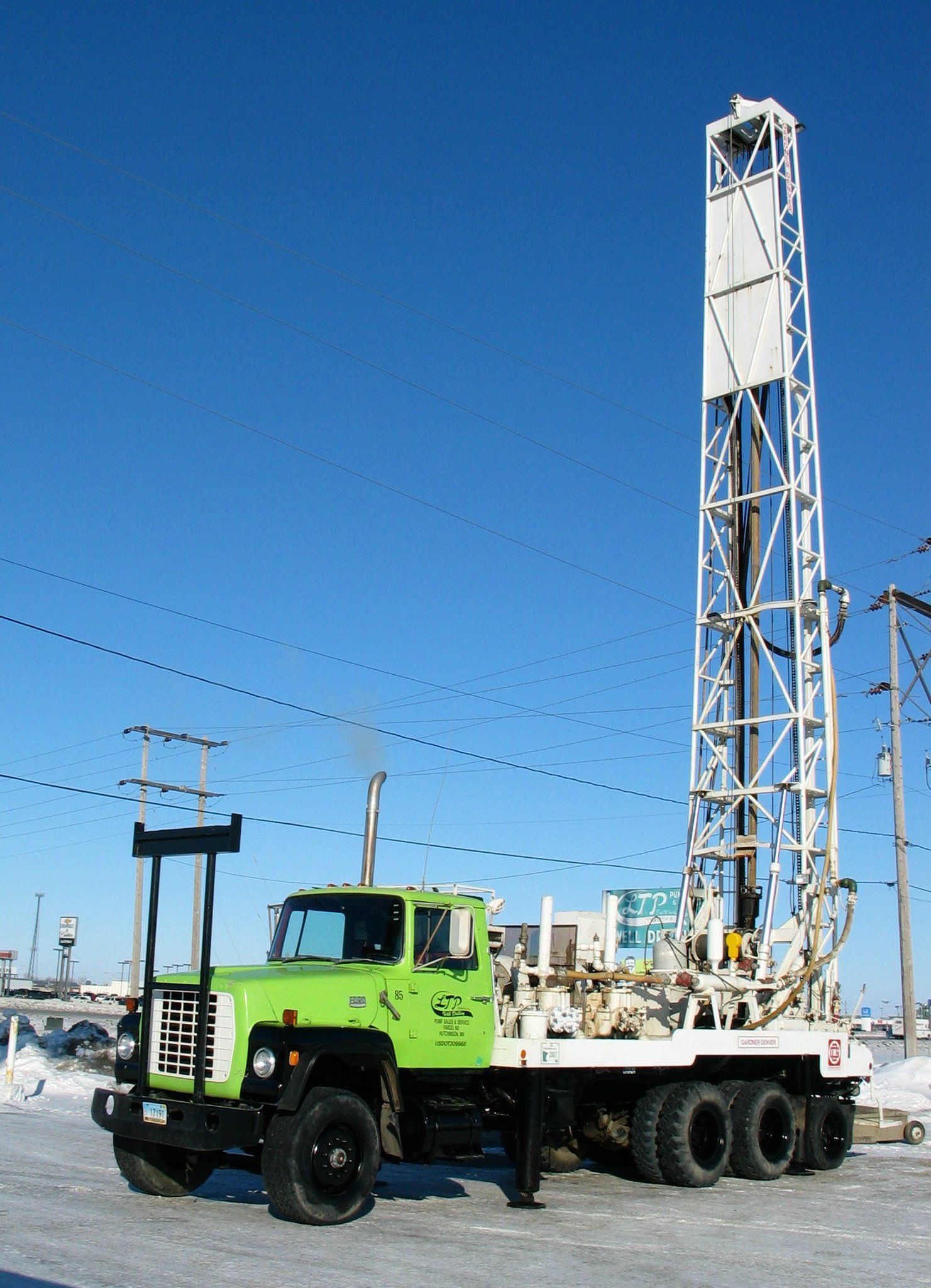 A green truck is parked next to a large white tower