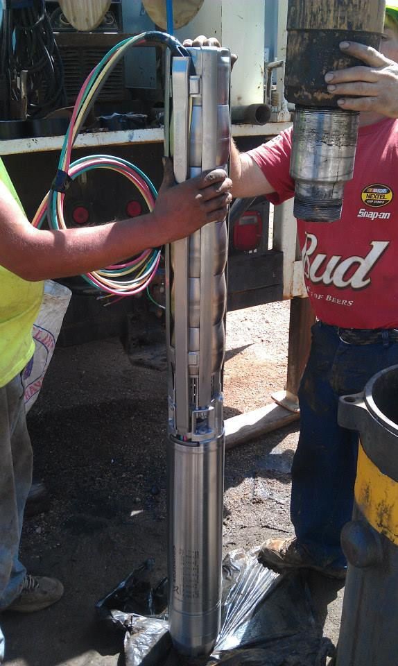 A man wearing a red bud shirt is working on a machine