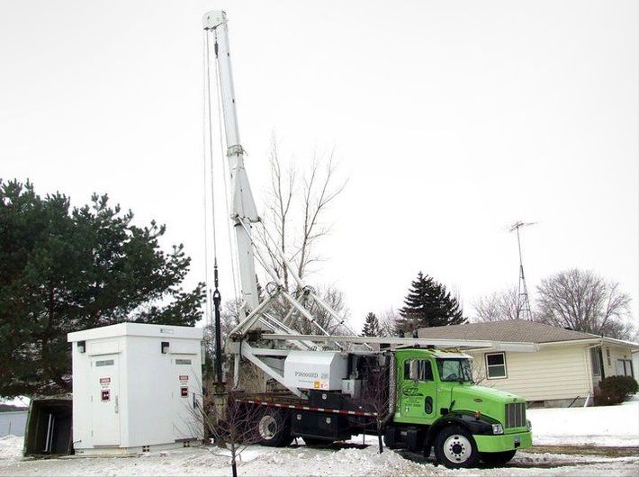 A green truck is parked in front of a house