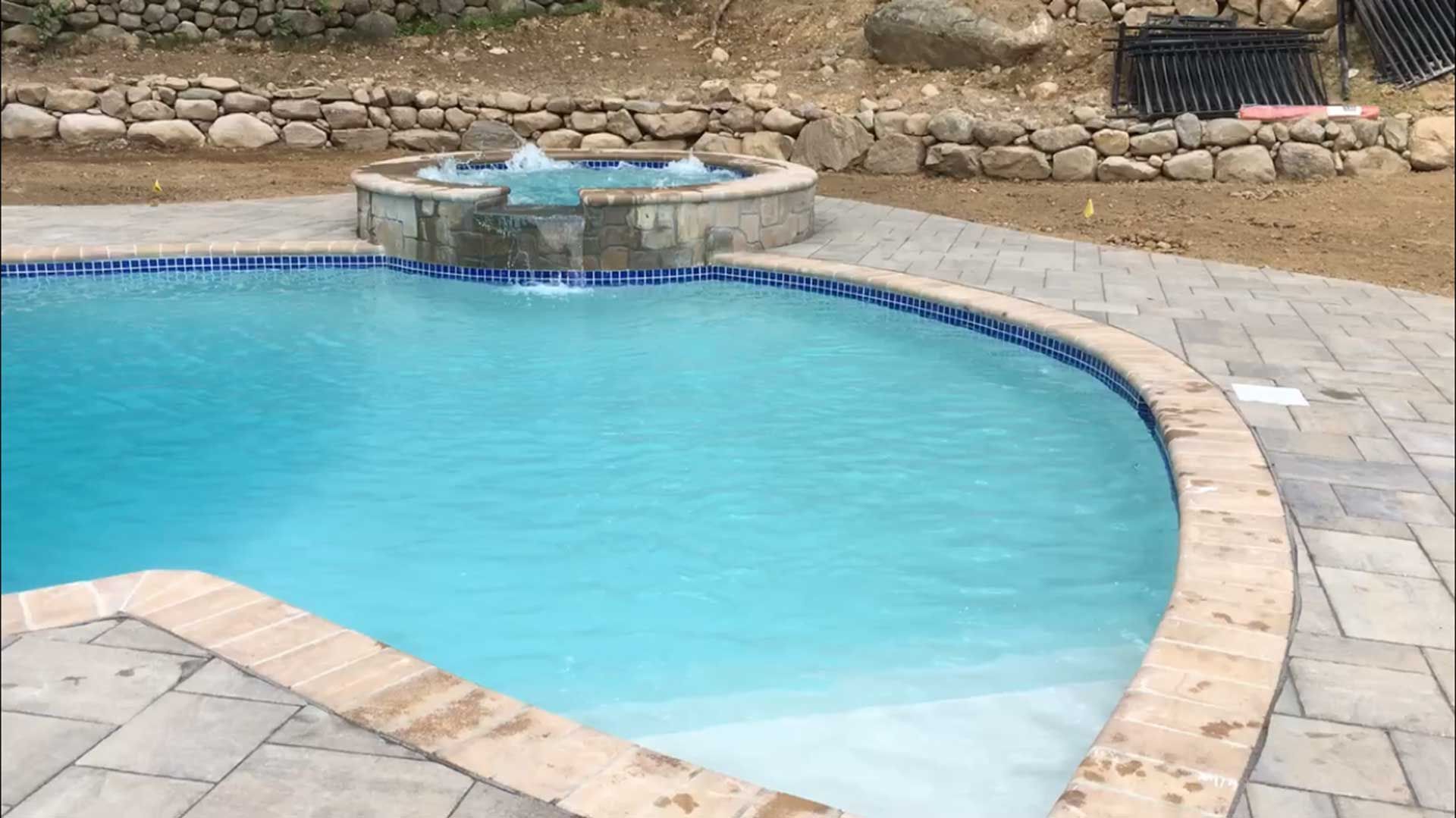 A large swimming pool with a hot tub in the middle of it