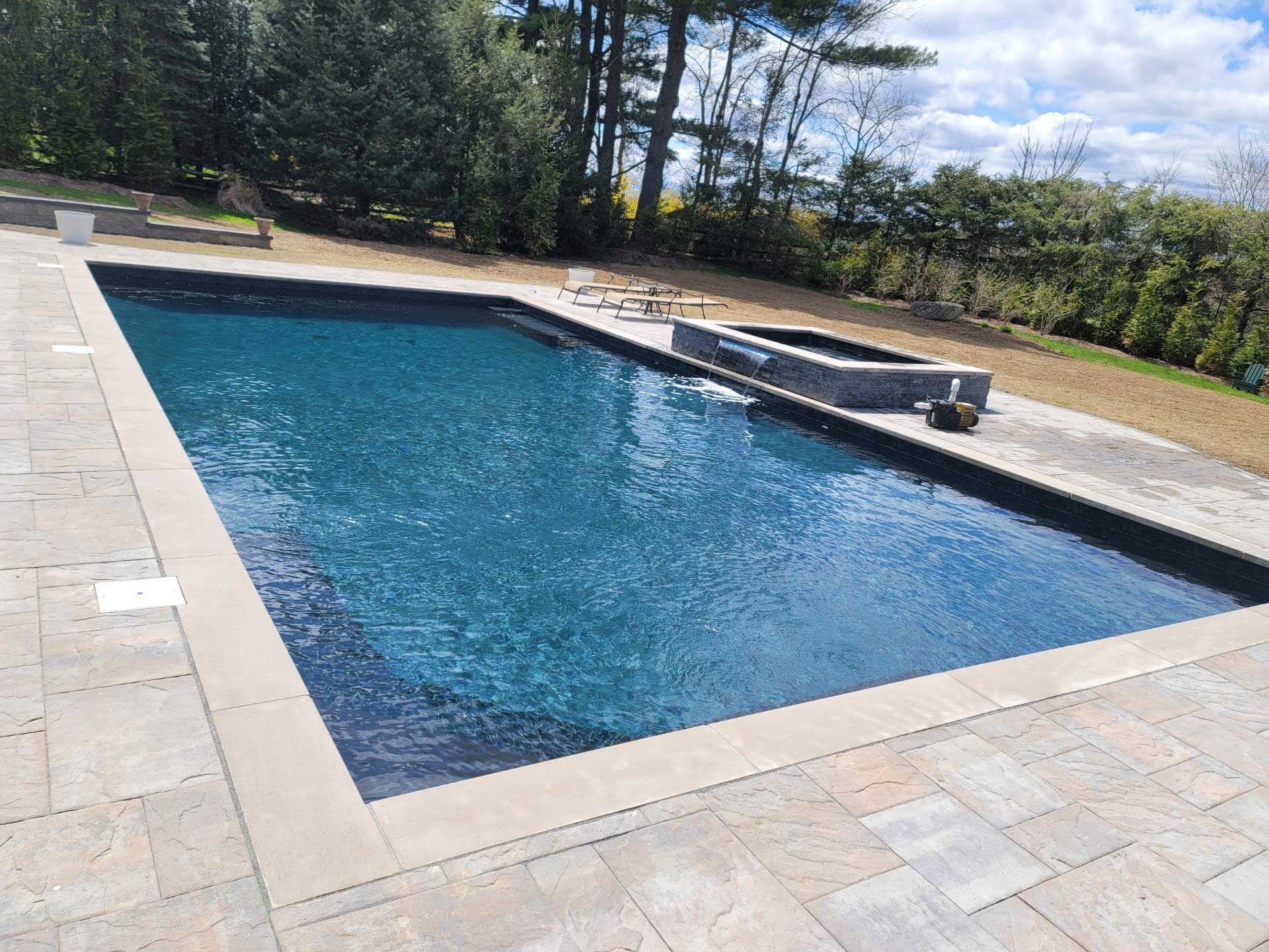 A large swimming pool is surrounded by trees and a patio