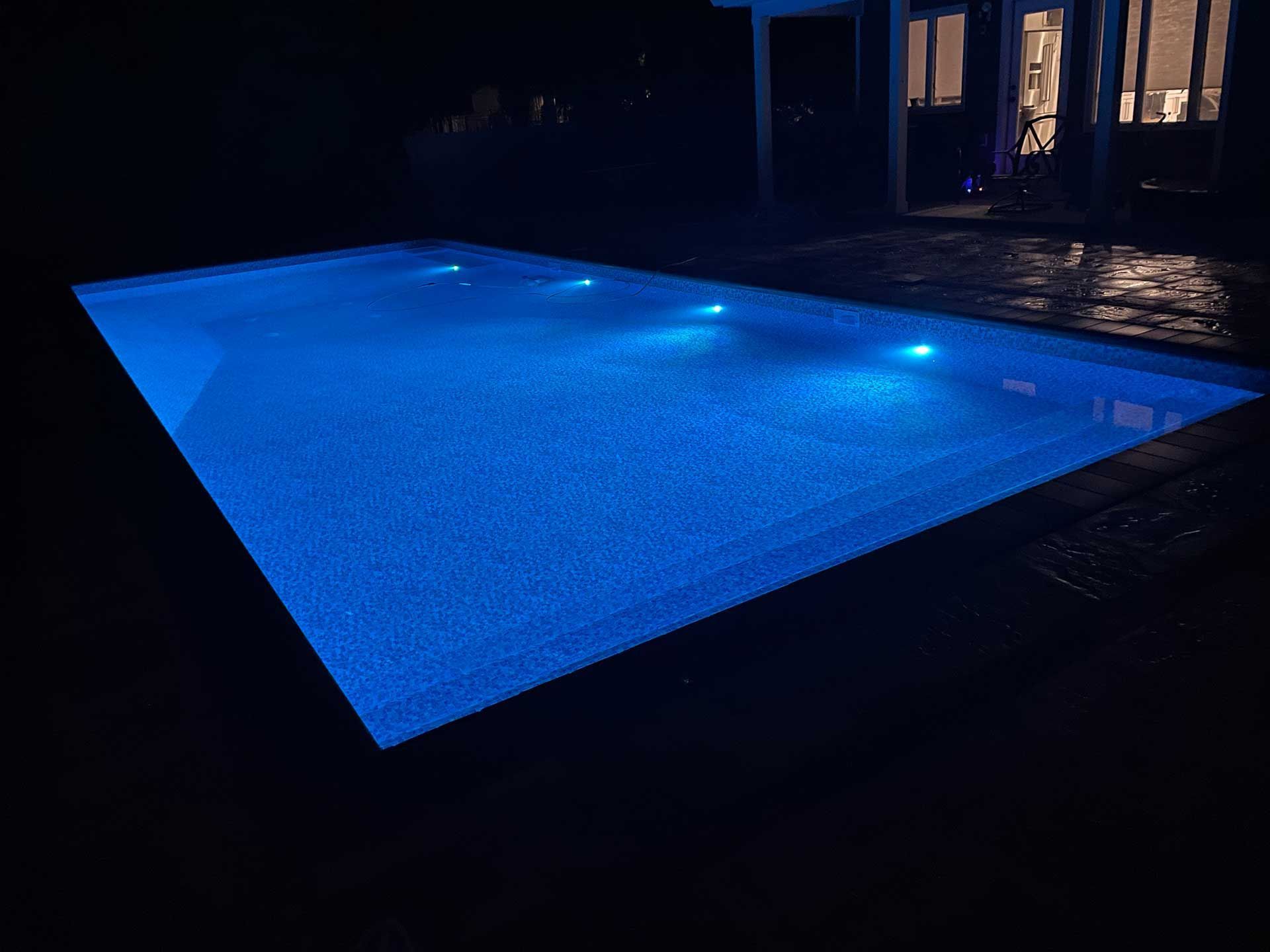 A large swimming pool is lit up with blue lights