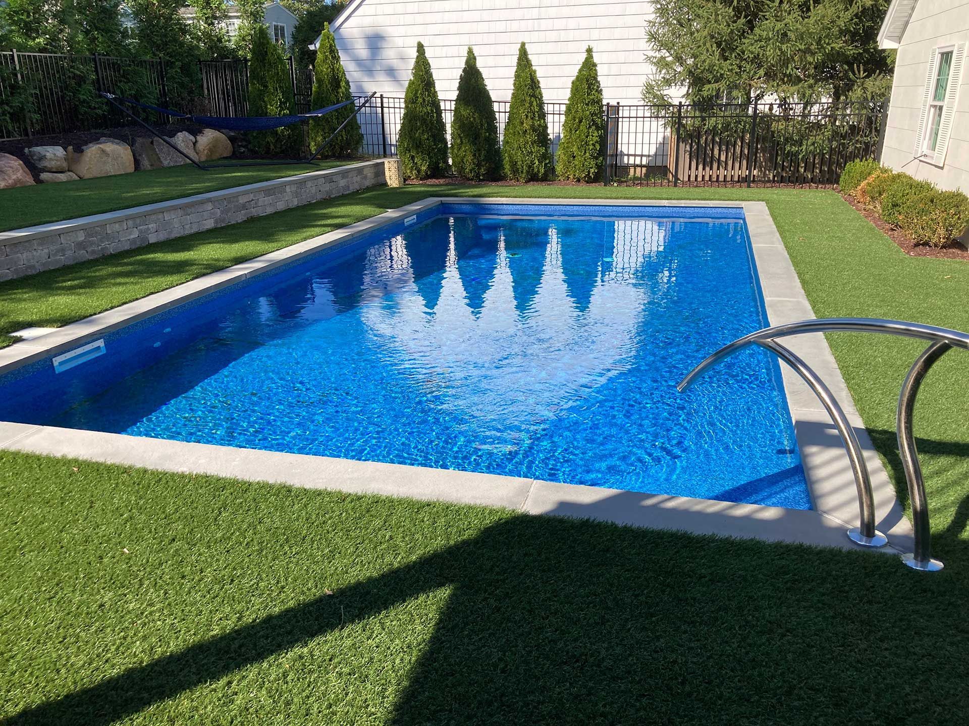 A large swimming pool surrounded by grass and trees in a backyard
